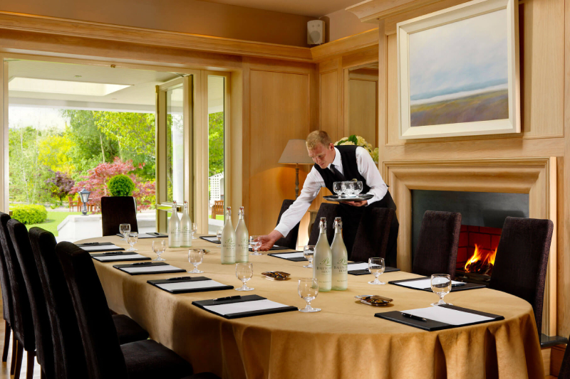 Elegant conference room setup at Ballygarry Estate, with a fireplace and garden view, offering a warm and professional atmosphere.